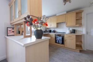 eine Küche mit einer Vase mit Blumen auf einer Theke in der Unterkunft Stunning 5 bedroom detached house in Hornchurch in Romford