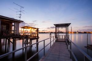 un muelle sobre un cuerpo de agua al atardecer en Bangkok Tree House Bang Kachao, en Bangkok