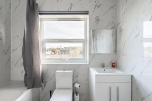 a white bathroom with a window and a sink at Cozy Downtown Apartment in Rochester +93 photos