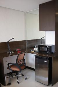 a room with a desk with a chair and a microwave at Regency Grand Suites in Manila