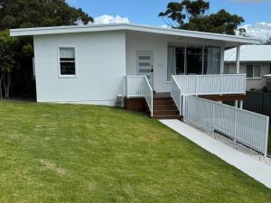 a white house with a lawn in front of it at Sunny Rose in Shellharbour