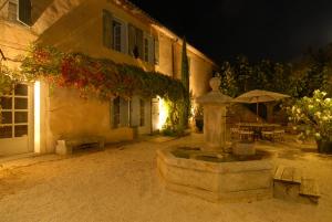 uma fonte de pedra em frente a um edifício à noite em Clos De La Fontaine em Cabrières-dʼAvignon