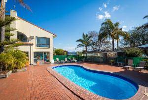 a swimming pool in front of a house at Aquarius Merimbula in Merimbula