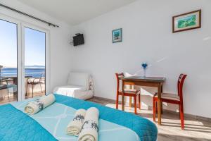 a bedroom with a bed and a desk and a balcony at Apartments by the sea Igrane, Makarska - 22690 in Igrane