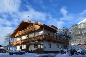 un edificio con una cruz en el techo en la nieve en Haus Almfriede, en Leutasch