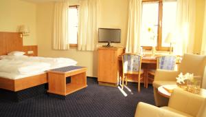 ein Hotelzimmer mit einem Bett und einem Tisch mit einem TV in der Unterkunft Hotel Gasthof Kreuz in Bad Buchau
