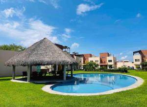 a large swimming pool with a thatch roof at Casa Sauces Sur, alberca, billar, roof garden privado in Emiliano Zapata