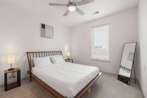 a white bedroom with a bed and a ceiling fan at Stunning Nulu 1BR of CozySuites 08 in Louisville