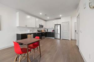 a kitchen with white cabinets and a table and red chairs at Stunning Nulu 1BR of CozySuites 08 in Louisville