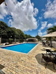 uma piscina com mesas e cadeiras e um guarda-sol em Aconchegante apt em Joao Pessoa em João Pessoa