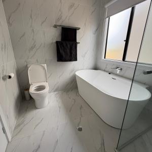 a white bathroom with a tub and a toilet at Goolwa Beach Pavilion in Goolwa South +30 photos