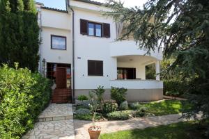 a white house with a garden in front of it at Apartment Klepac in Punat