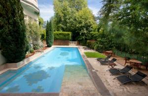 - une piscine avec des chaises et une table dans la cour dans l'établissement Belle Isle Sur Risle - Chateau Hotel & Spa, à Pont-Audemer