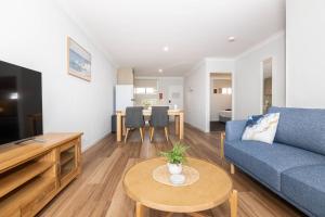 a living room with a blue couch and a table at Jurien Bay Motel Apartments in Jurien Bay