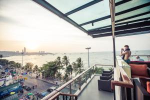 a man standing on a balcony looking at the ocean at Serenotel Pattaya in Pattaya