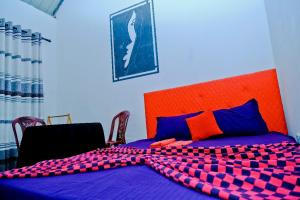 a bedroom with a purple bed with an orange headboard at Ninety Nine Grand Hotel in Badulla