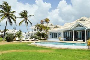 a white house with a swimming pool and palm trees at Rose Villa Tobago in Auchenskeoch