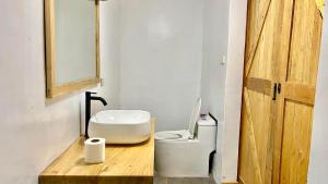 a bathroom with a white toilet and a wooden counter at AA Jungle Guesthouse in San Juan +28 photos