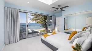 two beds in a bedroom with a view of the ocean at Foreshore Bliss in Salamander Bay +33 photos
