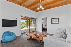 a living room with a couch and a table at Waitorupai Retreat 2 - Sandy Bay Holiday Home in Whangarei