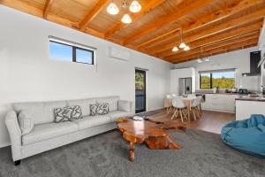 a living room with a couch and a table at Waitorupai Retreat 2 - Sandy Bay Holiday Home in Whangarei +9 photos