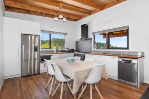 a kitchen with a table and chairs in a room at Waitorupai Retreat 2 - Sandy Bay Holiday Home in Whangarei