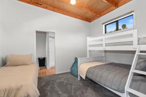 a bedroom with two bunk beds and a window at Waitorupai Retreat 2 - Sandy Bay Holiday Home in Whangarei