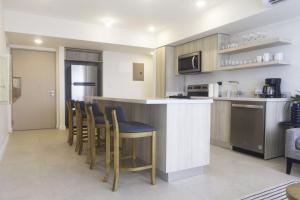 Una cocina con barra con sillas y microondas. en J-PacP506 condo, en Jacó