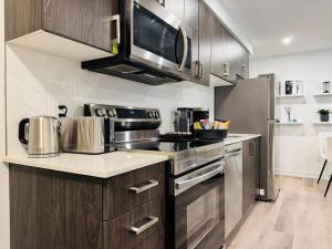 eine Küche mit Küchengeräten aus Edelstahl und einer Mikrowelle in der Unterkunft Luxury Stay Near Niagara Falls in Niagara Falls