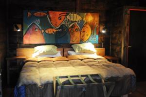 a bedroom with a large bed with a painting on the wall at Las Pitras Lodge in Epuyén