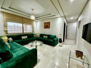 a living room with a green couch and a table at APT Luxueux à 5 min de la Plage avec accès Piscine in Bouznika