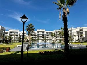 a large apartment building with a swimming pool and a street light at APT Luxueux à 5 min de la Plage avec accès Piscine in Bouznika