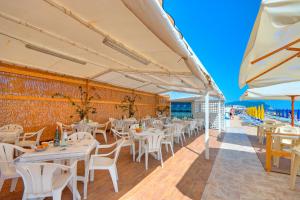 un restaurante con mesas y sillas blancas y la playa en Residence I Giardini Del Conero, en Porto Recanati