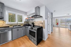 a kitchen with stainless steel appliances and wood floors at Ultimate Lakeview Retreat - Hot Tub, Paddle & Play in Bancroft