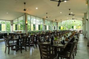 a dining room with tables and chairs and windows at Oak Ray Elephant Lake in Sigiriya