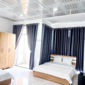 a bedroom with a bed with blue curtains and a window at Homestay Đức Thạnh in Rạch Giá