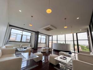 a living room with white furniture and large windows at Ananya Dorms in Hospet