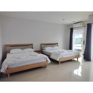 two twin beds in a room with a window at MikaHouse in Betong