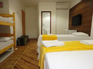 a hotel room with two beds and a television at Pousada Pedacinho da Bahia in Salvador