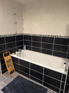 a bathroom with a white tub and black tiles at Maison cosy 2 chambres proche Troyes in Villacerf