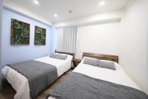 twee bedden in een kamer met blauwe muren bij Shibuya WAVE 302 in Tokyo