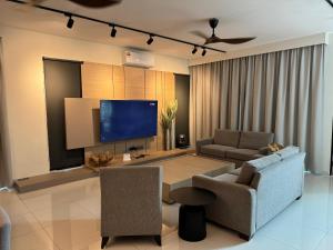 a living room with a tv and a couch and chairs at Ruma Langkawi in Kuah