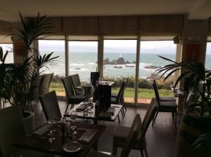 a restaurant with tables and chairs and a view of the ocean at Corbiere Phare Apartments in St Brelade