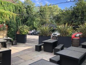a patio with tables and benches and potted plants at The Deeping Stage in Market Deeping