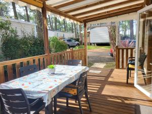 a wooden deck with a table and chairs on it at SevServices aux Dunes de Contis in Saint-Julien-en-Born