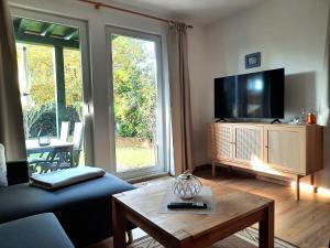 a living room with a tv and a couch and a table at Ferienhaus Sasse Ferienwohnungen mit Garten & Grill in Mölschow +24 photos