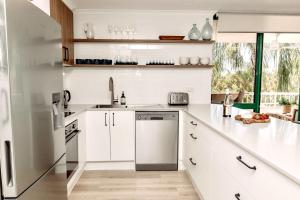 una cucina bianca con lavandino e lavastoviglie di Headlands Beachside Retreat - 50 metres to beach ad Alexandra Headland