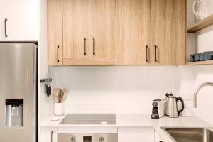 una cucina con elettrodomestici bianchi e armadietti in legno di Headlands Beachside Retreat - 50 metres to beach ad Alexandra Headland Altre 19 foto