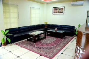 a living room with a black leather couch and a table at Hotel Dior Near Jal Mahal, Jaipur in Jaipur