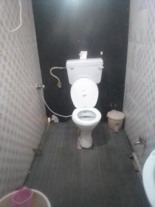 a bathroom with a white toilet in a stall at Himalayan Mountain View, Triund Trekking Hostel in Dharamshala